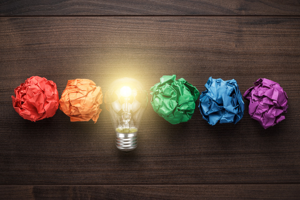 glowing light bulb lined up with colorful crumpled papers