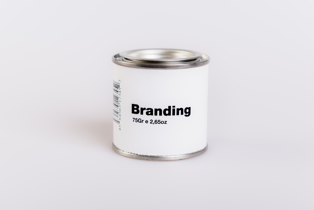 A tin can with a white label with text Branding on it
