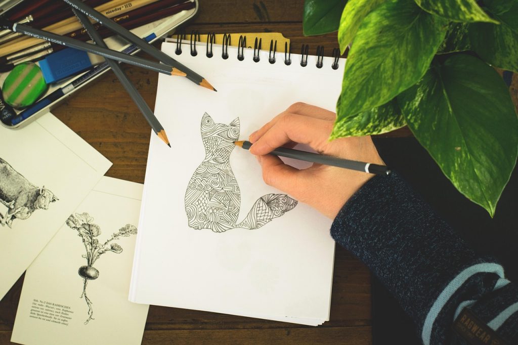Artist sketching creative ideas in a notebook to overcome art block